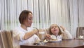 Beautiful Young Mother And Little Daughter Eat Cake Together In A Cozy Cafe