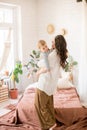 Beautiful young mother with long dark hair in homely comfortable clothes plays with her young son in a cozy bedroom Royalty Free Stock Photo