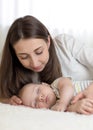 Beautiful mother looks at her 7 months old baby sleeping in the bed Royalty Free Stock Photo