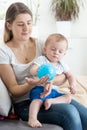 Beautiful young mother playing with her baby boy on sofa with ba Royalty Free Stock Photo