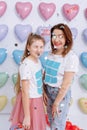 Beautiful Young Mother And A Pretty Little Daughter, The Family On A Colorful Hearts Background, Are Smiles, Funny