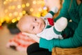 Beautiful young mother with red hair  holds a baby in her arms at home in a room decorated with Christmas garlands, needles. Royalty Free Stock Photo