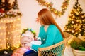 Beautiful young mother with red hair  holds a baby in her arms at home in a room decorated with Christmas garlands, needles. Royalty Free Stock Photo