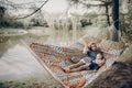 Beautiful young mother resting on hammock near a lake with her little child, family vacation concept, mother and son on a camping Royalty Free Stock Photo