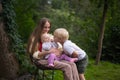 Beautiful young mother sitting with two children on nature background. Vacation with children. Happy family concept Royalty Free Stock Photo