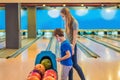 beautiful young mother and son playing bowling with medical masks during COVID-19 coronavirus in bowling club Royalty Free Stock Photo