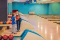 beautiful young mother and son playing bowling with medical masks during COVID-19 coronavirus in bowling club Royalty Free Stock Photo