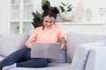 Beautiful young mother uses a laptop and smiling while sitting on sofa at home Royalty Free Stock Photo