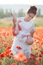 A happy mother with a small son in her arms on the endless field of red poppies on a sunny summer day Royalty Free Stock Photo