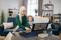 Mother teaching cute little musician girl to play piano.