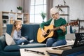 Mother teaching cute little musician girl to play guitar.