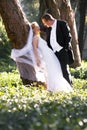 Beautiful young newly wed couple leaning against tree trunk in forest Royalty Free Stock Photo