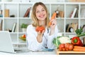 Beautiful young nutritionist looking at camera and holding fresh vegetables in the consultation.