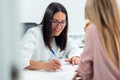 Beautiful young nutritionist woman explaining to her patient the diet he should follow to lose weight in the consultation