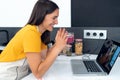 Beautiful young nutritionist woman having an online video call via laptop computer with a friend in the kitchen at home Royalty Free Stock Photo