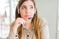 Beautiful young operator woman wearing headset at the office with hand on chin thinking about question, pensive expression Royalty Free Stock Photo