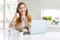 Beautiful young operator woman working with laptop and wearing headseat doing happy thumbs up gesture with hand Royalty Free Stock Photo