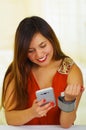 Beautiful young patient using an automatic tensiometer in her arm and texting in her cellphone, in a doctor consulting