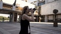 Beautiful young photographer woman takes photos outdoors of a modern business district. Action. Camera moving around a Royalty Free Stock Photo