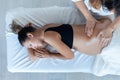 Beautiful young physiotherapist woman massaging tummy on pregnant woman on a stretcher at home