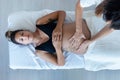 Beautiful young physiotherapist woman massaging tummy on pregnant woman on a stretcher at home Royalty Free Stock Photo