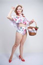 Beautiful young pin up caucasian girl in romantic fashionable straw hat, vintage swimsuit with flowers and retro wicker basket pos Royalty Free Stock Photo