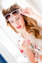 Beautiful young pinup girl having fun reading message on mobile cell phone and wearing sunglasses closeup portrait picture Royalty Free Stock Photo