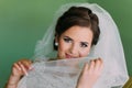 Beautiful young playful bride hiding her face behind veil