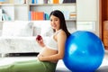 Beautiful young pregnant asian woman holding apple and lean against exercise ball in living room at house with smiley face and Royalty Free Stock Photo