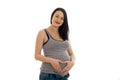 Beautiful young pregnant brunette woman touching her belly and looking at the camera isolated on white background Royalty Free Stock Photo