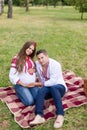Beautiful young pregnant couple dressed in national ukrainian style having picnic in autumn park. Maternity and family happyness