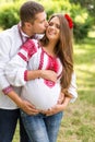 Beautiful young pregnant couple dressed in national ukrainian style kissing in autumn park. Maternity and family happiness concept Royalty Free Stock Photo