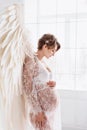 Beautiful young pregnant girl with big angel wings Royalty Free Stock Photo