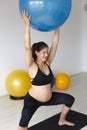 Beautiful, young, fit, athletic and pregnant woman with black hair doing fitness exercises in a modern apartment Royalty Free Stock Photo