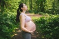 Beautiful young pregnant woman doing yoga exercising in park outdoor. Sitting and relaxing on pink yoga mat. Active future mother Royalty Free Stock Photo