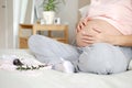 Young pregnant woman in home clothes strokes her big belly Royalty Free Stock Photo