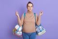 Beautiful young pregnant woman with hair bun meditates before going to maternity home to give birth, trying to relax, holding