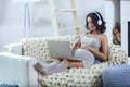 Beautiful young pregnant woman with laptop sitting on sofa at home Royalty Free Stock Photo