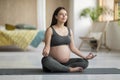 Beautiful young pregnant woman in practicing yoga in lotus position at home Royalty Free Stock Photo