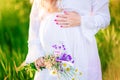 Beautiful young pregnant woman relaxing in nature on a beautiful sunny day. Close up of pregnant belly in nature Royalty Free Stock Photo