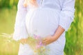 Beautiful young pregnant woman relaxing in nature on a beautiful sunny day. Close up of pregnant belly in nature Royalty Free Stock Photo