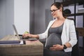 Young pregnant business woman using a laptop in the office Royalty Free Stock Photo