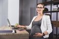 Young pregnant business woman using a laptop in the office Royalty Free Stock Photo