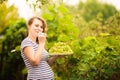 A beautiful young pregnant woman is standing in the summer near a vine grape