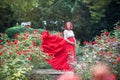 Beautiful young pregnant woman walking in the field of roses wit