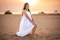 Beautiful young pregnant woman in white dress posing on the beach at sunset. Royalty Free Stock Photo