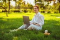 Beautiful young pretty redhead woman in park outdoors using laptop computer for study or work online, wireless Royalty Free Stock Photo