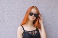 Beautiful young red hair woman in sunglasses on textured background Royalty Free Stock Photo