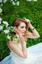 A beautiful young red-haired woman enjoys life in a spring blooming garden with a background of flowering trees. Dreamy pensive Royalty Free Stock Photo