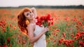 Beautiful young red-haired woman in poppy field holding a bouquet of poppies Royalty Free Stock Photo